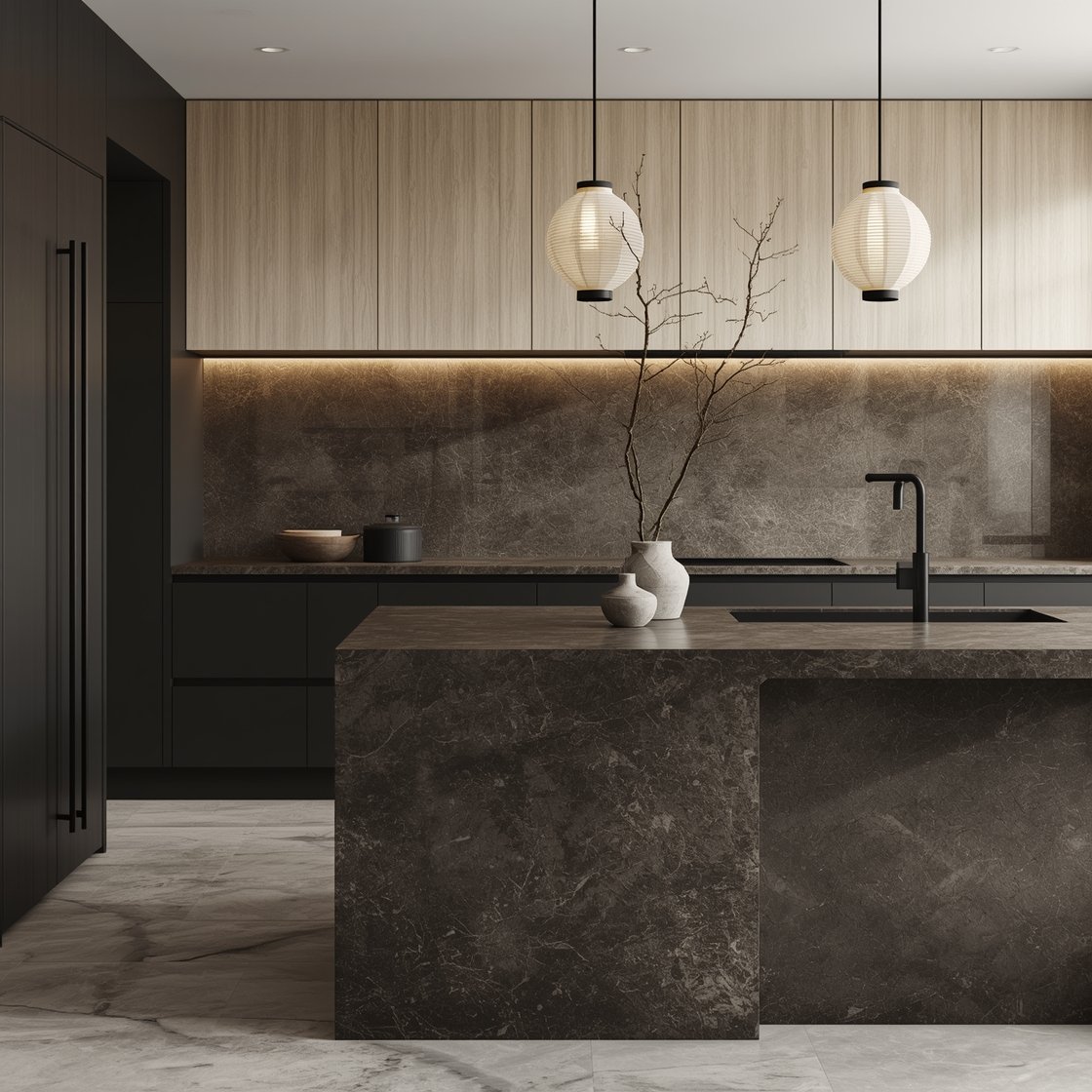 Wide shot, clean straight-on: Japandi nightfall kitchen with base cabinets in soft black ash veneer and pale ash-wood uppers with minimal frames, a sculptural island block with a rounded corner and waterfall of dark honed granite, seamless deep taupe microcement backsplash, discreet black edge pulls, paper lantern pendants floating above, a single branch in a stone vase on the island, ultra-tidy drawers implied; palette of soft black, ash wood, warm beige stone; serene, diffuse ambient light emphasizing negative space and tactile calm; photorealistic, no people.